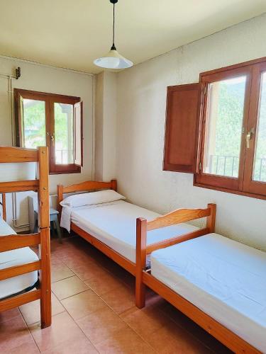 a room with three beds and two windows at Alberg rural torre del baró in Sant Llorenc de Morunys