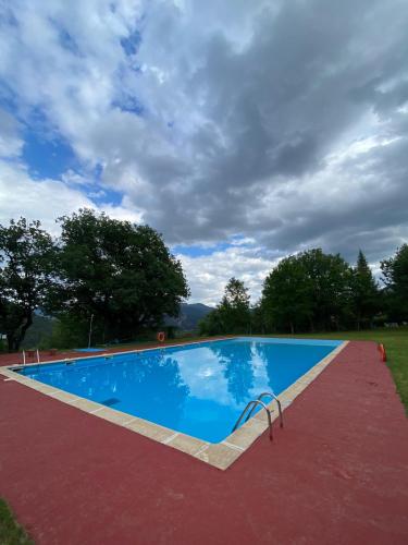 a blue swimming pool with a cloudy sky in the background at Alberg rural torre del baró in Sant Llorenc de Morunys