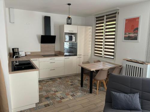 une cuisine avec des armoires blanches et une table en bois dans l'établissement el apartamento de julia, à Carcassonne