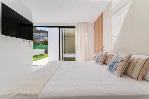 Un dormitorio con una cama blanca y un televisor de pantalla plana. en Casa Sicilia, en Puerto Rico de Gran Canaria