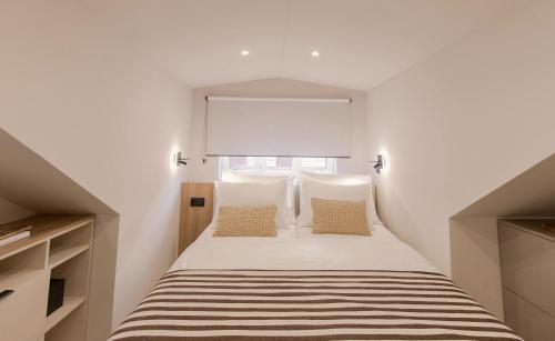 a bedroom with a bed with white walls and a window at Velut Home Bural in Dubrovnik