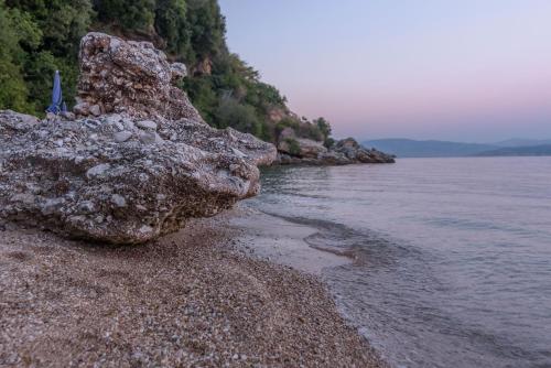 a large rock sitting on a beach next to the water at Akrogiali Apartments in Barbati