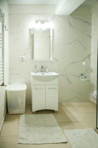 a white bathroom with a sink and a mirror at Studio Deluxe Astoria Lake in Năvodari