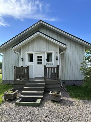 a white building with a porch with two benches at House and guest house with sauna by the sea in Närpiö
