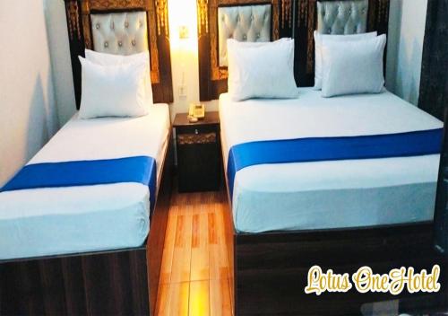 two beds sitting next to each other in a room at Lotus One Hotel in Lahore