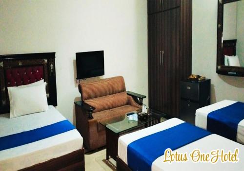 a hotel room with two beds and a chair at Lotus One Hotel in Lahore