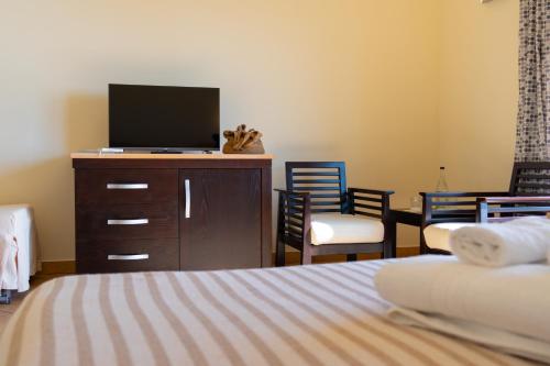 a bedroom with a bed and a tv and chairs at Hotel Garden in Praia a Mare