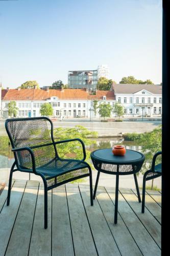 a patio with two chairs and a table and a window at Cobergher Hotel in Kortrijk