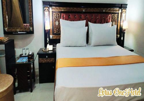 a bedroom with a large bed with a wooden headboard at Lotus One Hotel in Lahore