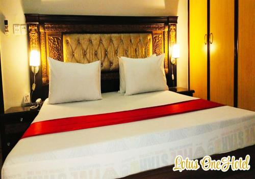 a large bed with a wooden headboard and white pillows at Lotus One Hotel in Lahore