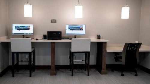 an office with two monitors on a desk with chairs at Staybridge Suites Auburn Hills by IHG in Auburn Hills