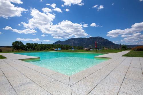a swimming pool with a blue sky and mountains at Agriturismo Piperedda in Irgoli