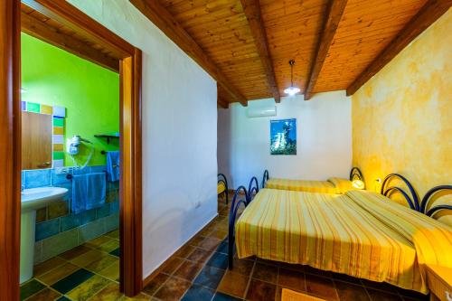a bedroom with a bed and a bathroom with a sink at Agriturismo Piperedda in Irgoli