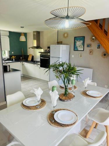 - une table à manger blanche avec des assiettes et des chaises blanches dans l'établissement Maison vacance proche ste mère église, à Picauville
