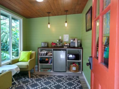 a green room with a refrigerator and a chair at Hale 'Ohu Bed & Breakfast in Volcano