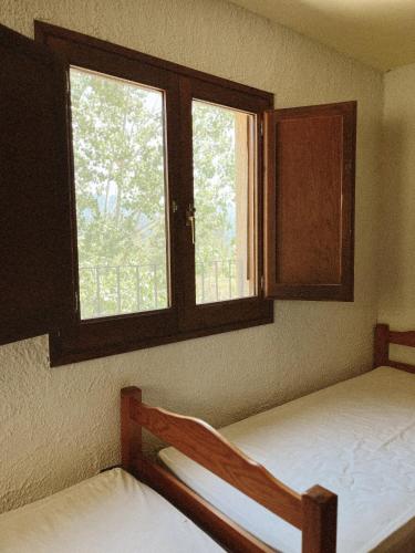 two beds in a room with two windows at Alberg rural torre del baró in Sant Llorenc de Morunys