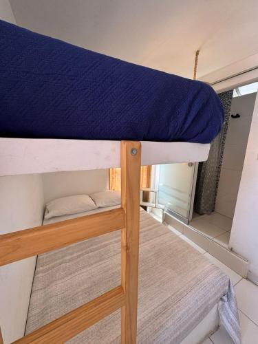a bunk bed with a blue pillow on top at Surfer Hostel El Quilla Punta Hermosa in Punta Hermosa