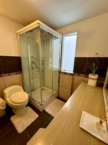 a bathroom with a glass shower and a toilet at Surfer Hostel El Quilla Punta Hermosa in Punta Hermosa