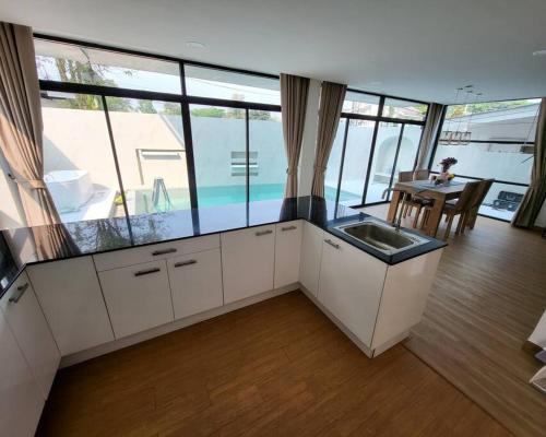 a kitchen with a sink and a table and some windows at The Joy Private Pool Villa in Chiang Mai