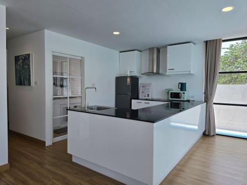 a white kitchen with a black counter top at The Joy Private Pool Villa in Chiang Mai