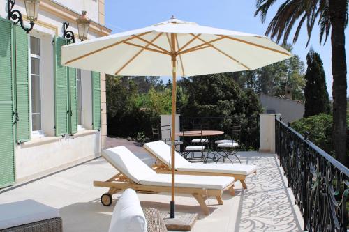 un patio avec une table, des chaises et un parasol dans l'établissement Villa Les Beaux Jours - Vue mer - Piscine - Jardin - Centre ville, à Saint-Raphaël