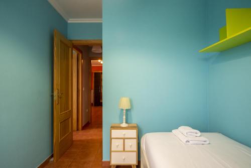 una stanza blu con un letto e una lampada sul comodino di Apartamento Ruiloba-Comillas a Casasola
