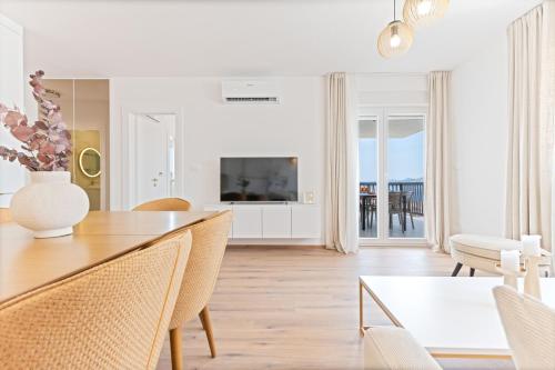 a white living room with a dining table and a television at Lush Suites in Trogir