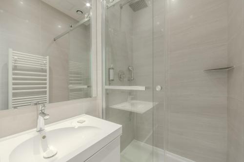 パリにあるジャルダン サント ノレ アパートメンツの洗面台とシャワー付きの白いバスルーム