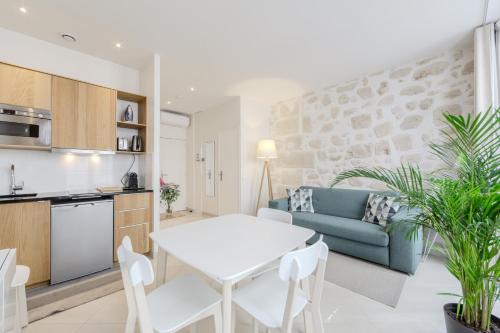 une cuisine et un salon avec une table et des chaises blanches dans l'établissement Jardin Saint Honoré Apartments, à Paris