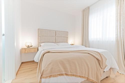 a white bedroom with a large bed and a window at Lush Suites in Trogir
