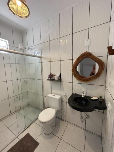 a white tiled bathroom with a toilet and a sink at Pousada Isabel Araújo in Jericoacoara