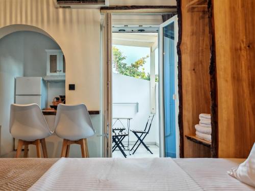 a bedroom with a bed and two chairs and a kitchen at Paraga Suites in Naxos Chora