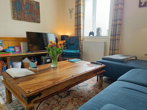 a living room with a coffee table and a blue couch at Snowberry Cottage in Borve