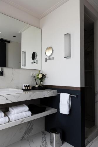 a bathroom with a sink and a mirror and towels at Cobergher Hotel in Kortrijk