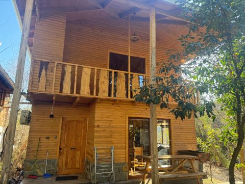 a wooden house with a balcony and a porch at Cabañas Arcos del salto del laja in El Manzano