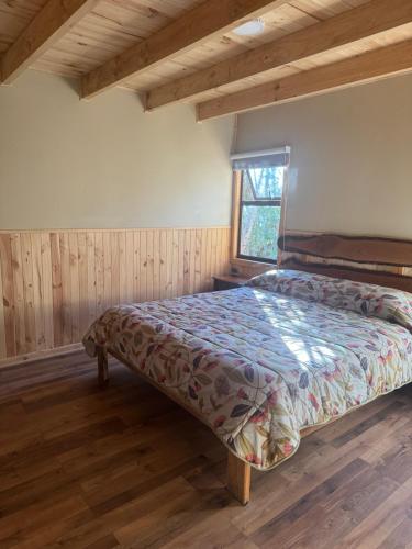 a bedroom with a bed in a room with wooden floors at Cabañas Arcos del salto del laja in El Manzano