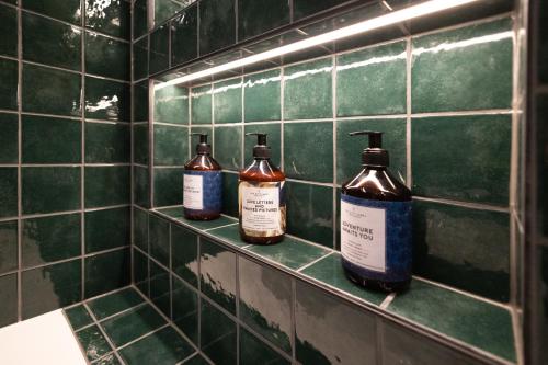 three bottles of soap sitting on a shelf in a bathroom at De Ware Jacob Boutique Hotel in Amsterdam
