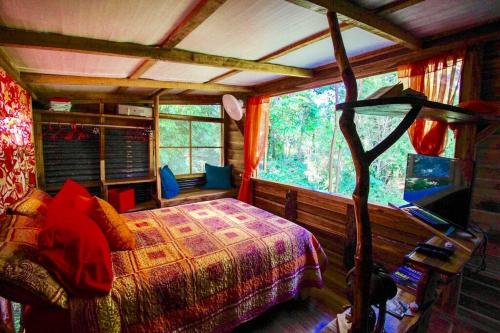 a bedroom with a bed and a large window at A Treehouse the Green Frog Romantic setting & Pool in Puerto Viejo
