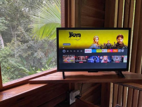 a flat screen tv sitting on a shelf next to a window at A Treehouse the Green Frog Romantic setting & Pool in Puerto Viejo