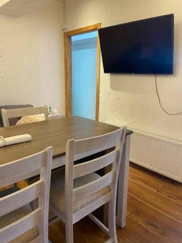 a wooden table with chairs and a television on a wall at Agathas Apartment - departamento céntrico in Punta Arenas