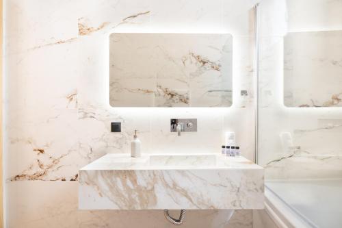 a white marble bathroom with a sink and a mirror at Petradi Suites in Kalamata