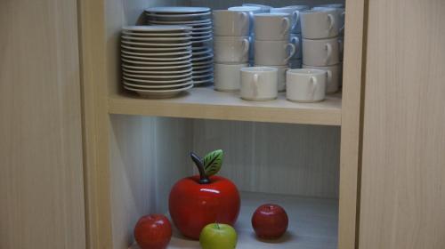 a cabinet with a red tomato and plates and cups at Pinheiros Hotel in Goiânia