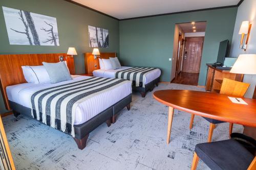 a hotel room with two beds and a table at Park Lake Luxury Hotel in Pucón