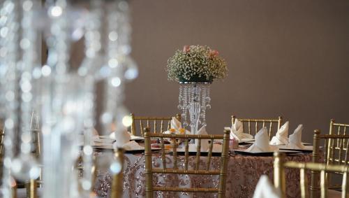a table with chairs and a vase with flowers on it at Hotel Colón Plaza Business Class in Nuevo Laredo