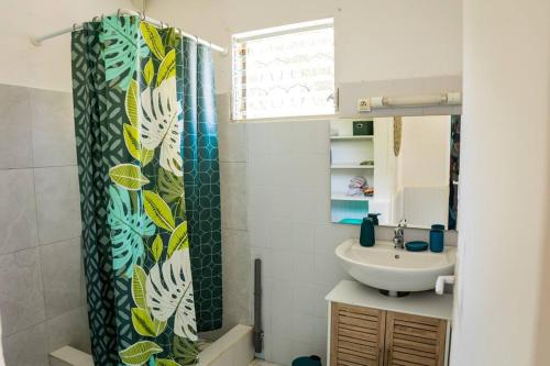 a bathroom with a sink and a shower curtain at Bungalow Saphir in Le Gosier