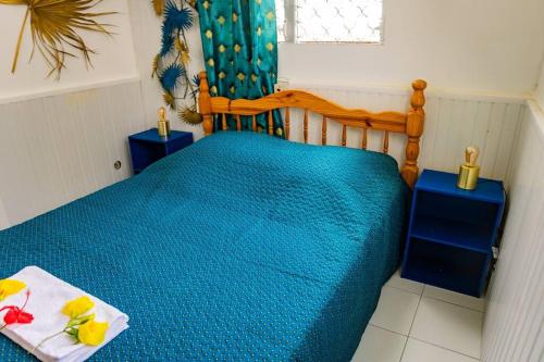 a bedroom with a bed with a blue comforter at Bungalow Saphir in Le Gosier