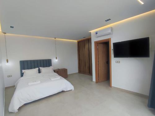 Un dormitorio con una cama y un televisor de pantalla plana. en Casa del mar, en Agadir nʼ Aït Sa