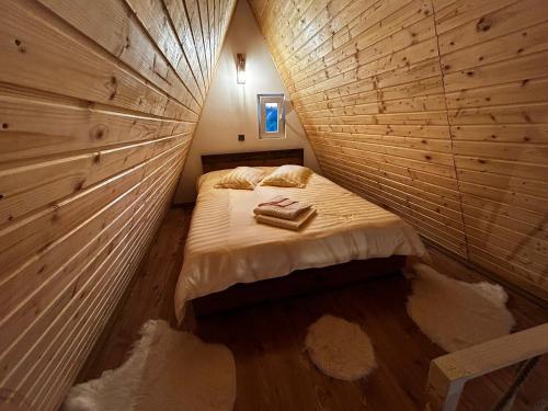 a small room with a bed in a wooden wall at Casuțele de la răscruce in Uric