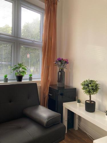 a living room with a couch and flowers in a window at Ocean waves apartment near Bournemouth beach in Bournemouth