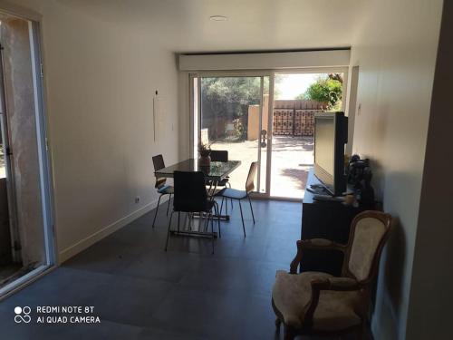 d'un salon avec une table, des chaises et une porte coulissante en verre. dans l'établissement La cigalière, au Beausset
